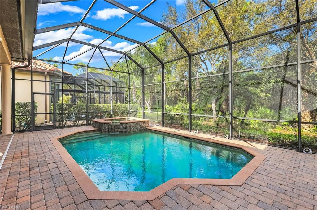 Integrated pool / hot tub featuring a sunroom, a lanai, and a patio