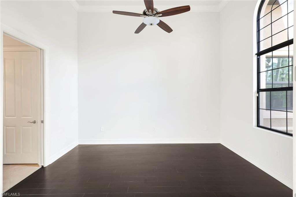 Spare room with dark wood-style flooring, ornamental molding, and a ceiling fan
