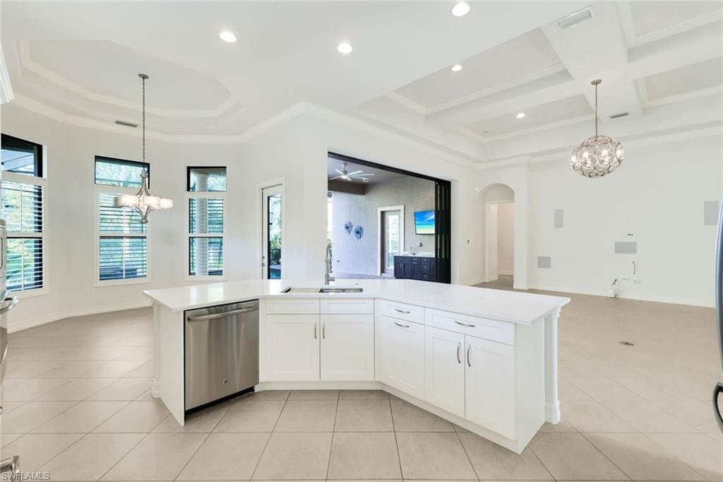 Kitchen featuring hanging lights, white cabinets, an island with sink, open floor plan, and stainless steel dishwasher