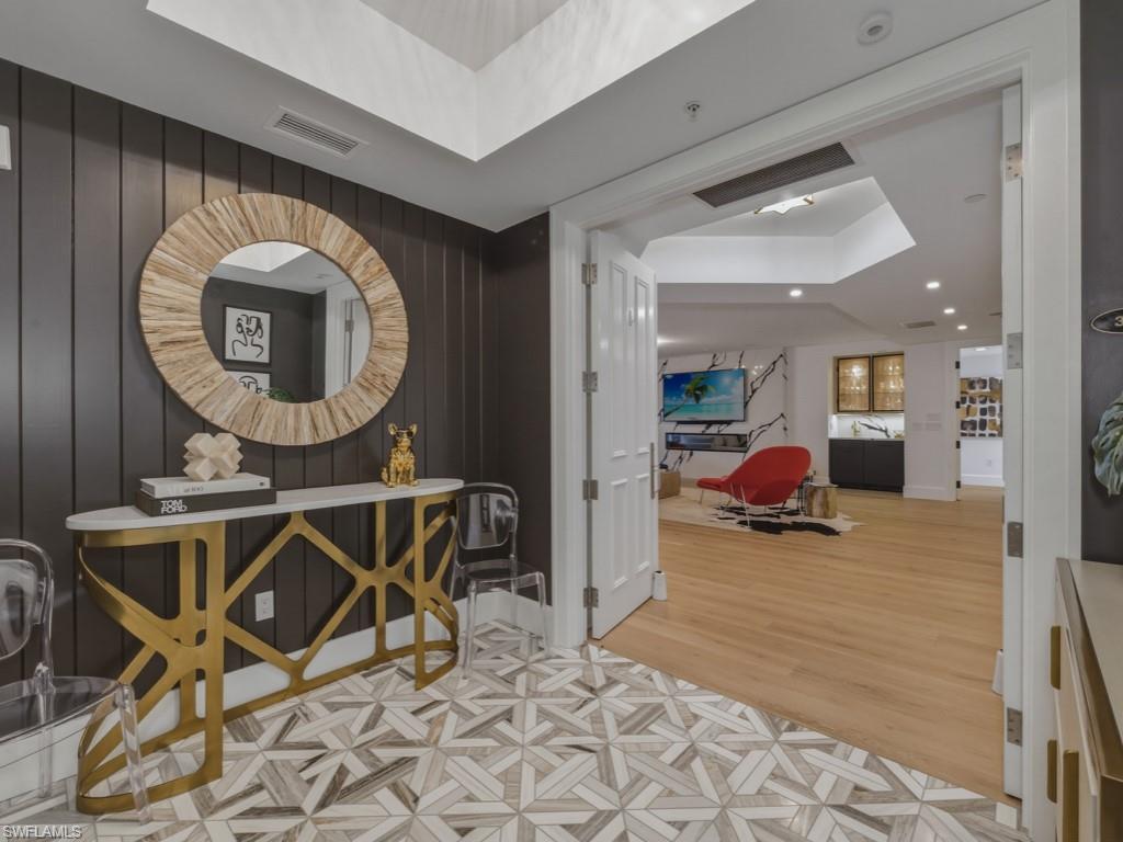 Hallway featuring a tray ceiling, marble flooring, wood accent wall, and recessed lighting