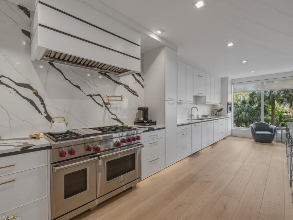 Kitchen featuring range with two ovens, decorative backsplash, white cabinetry, light wood-style floors, and recessed lighting