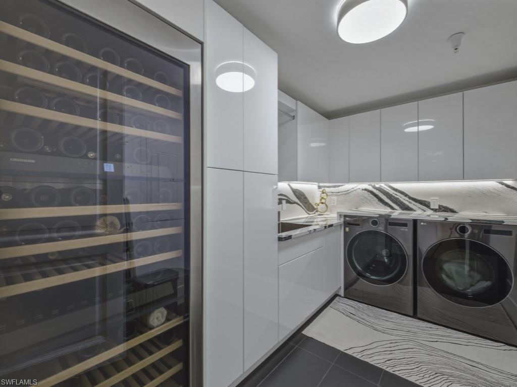 Laundry area with wine refrigerator, quartz counters, and separate washer and dryer