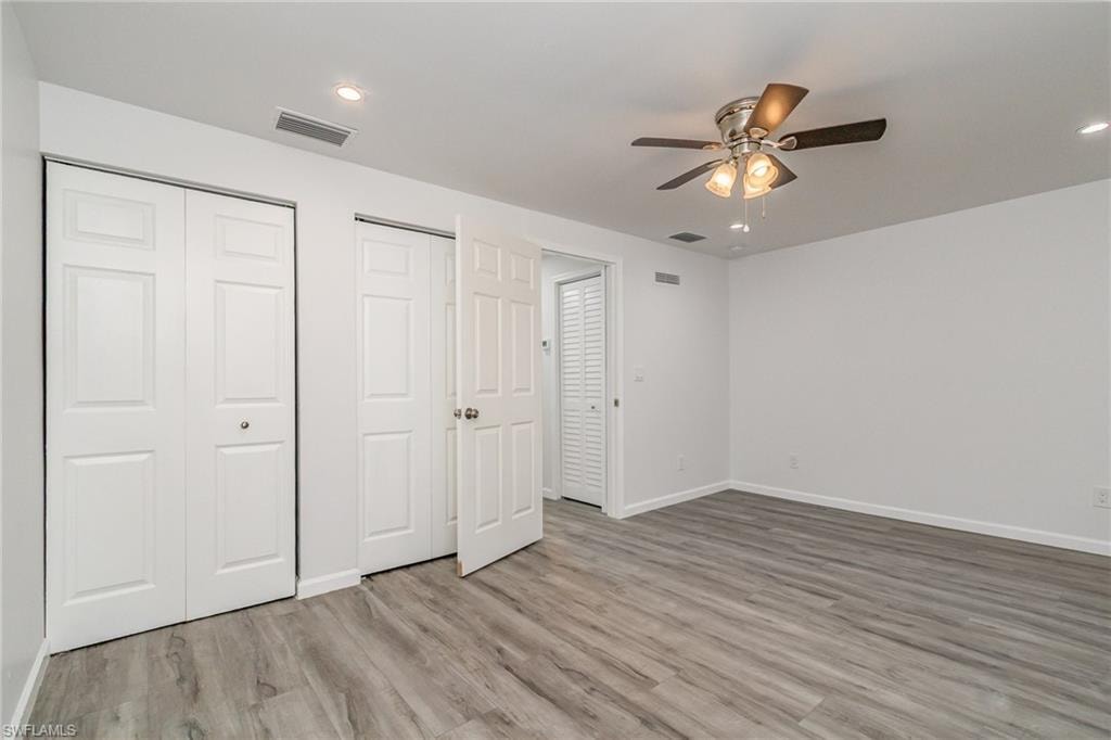 Unfurnished bedroom with two closets, a ceiling fan, light wood-style floors, and recessed lighting