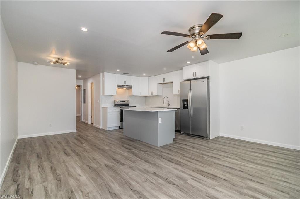 Kitchen with open floor plan, stainless steel appliances, ceiling fan, a kitchen island, and recessed lighting