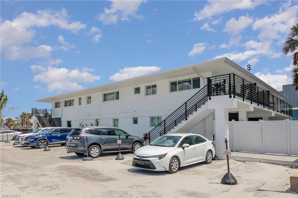 View of building exterior featuring stairs and uncovered parking