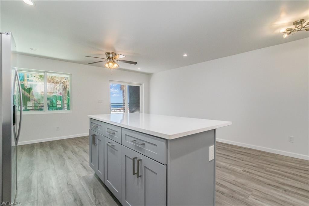 Kitchen with gray cabinets, stainless steel fridge with ice dispenser, ceiling fan, a kitchen island, and recessed lighting