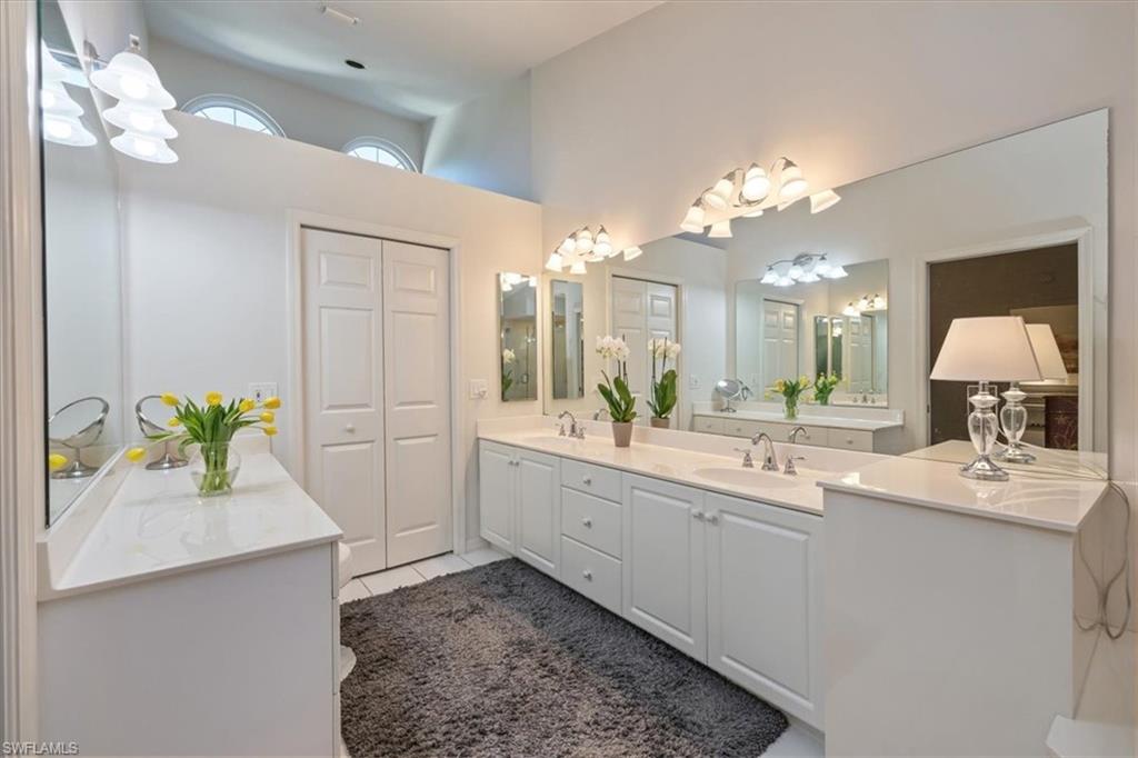 The primary bath offers dual vanities, a luxurious soaking tub, and a separate glass-enclosed shower, all opening to a spacious walk-in closet illuminated by a large window and abundant natural light.