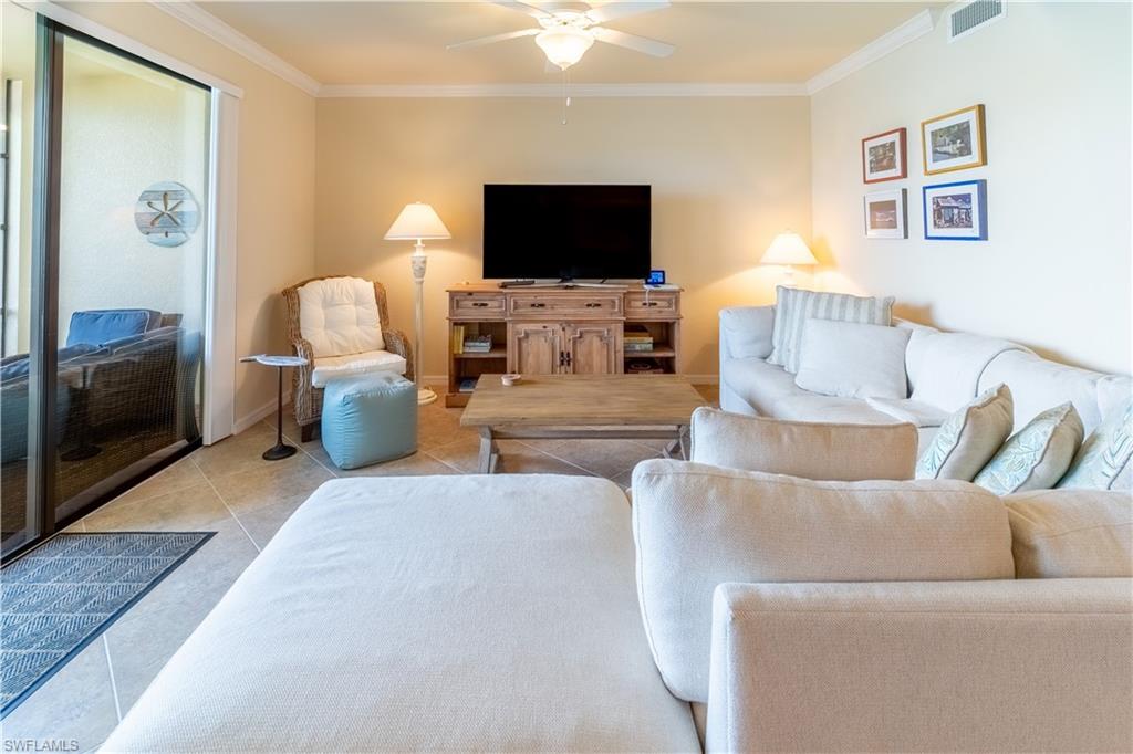 Tiled living area featuring crown molding and ceiling fan