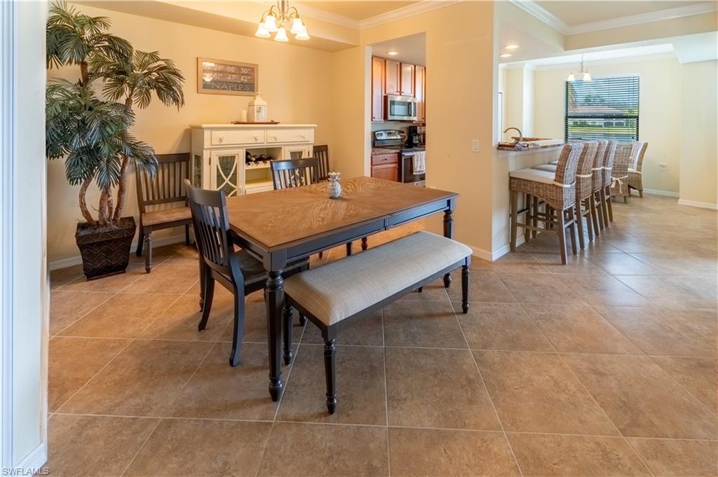 Dining room featuring hanging lights, ornamental molding, and light tile patterned flooring
