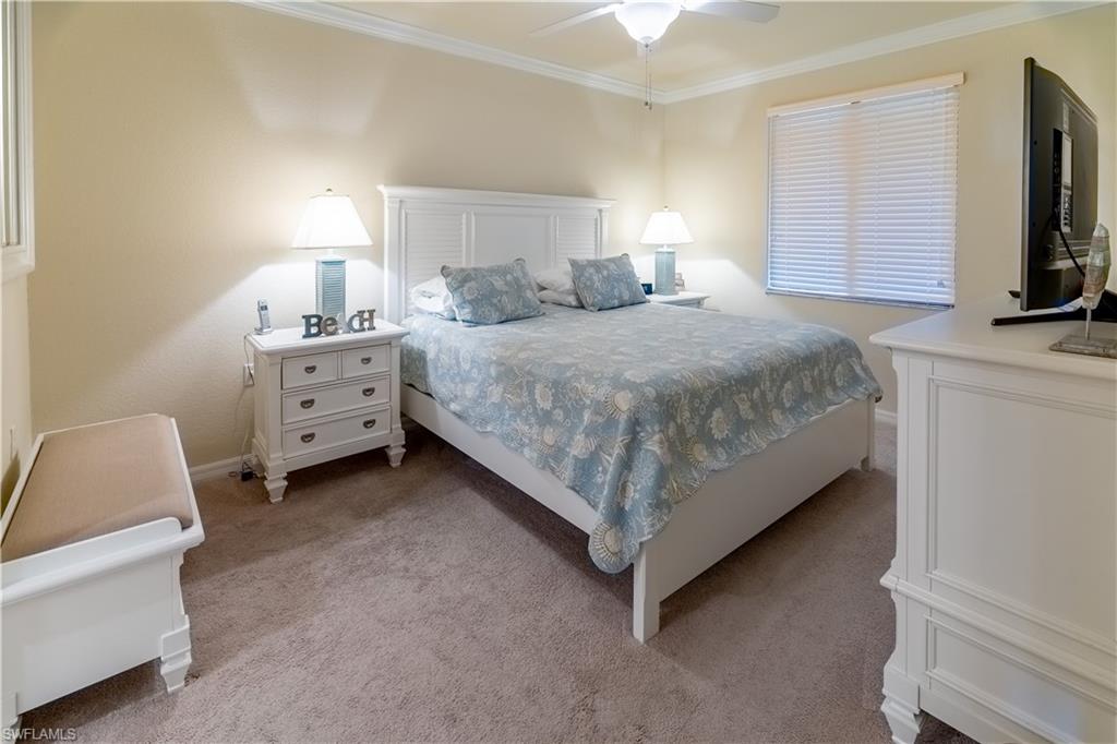 Bedroom with crown molding, light colored carpet, and a ceiling fan