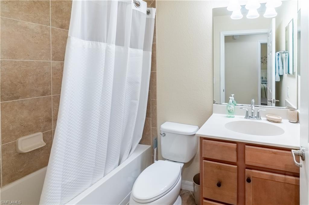 Full bathroom with vanity, shower / bath combo, and a textured wall