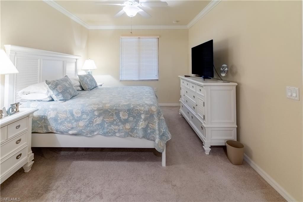 Bedroom with ornamental molding, light carpet, and ceiling fan