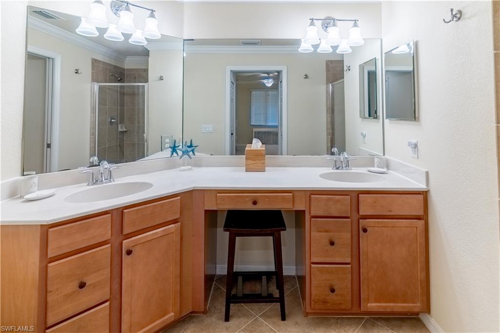 Full bathroom with double vanity, a shower stall, a chandelier, and ornamental molding