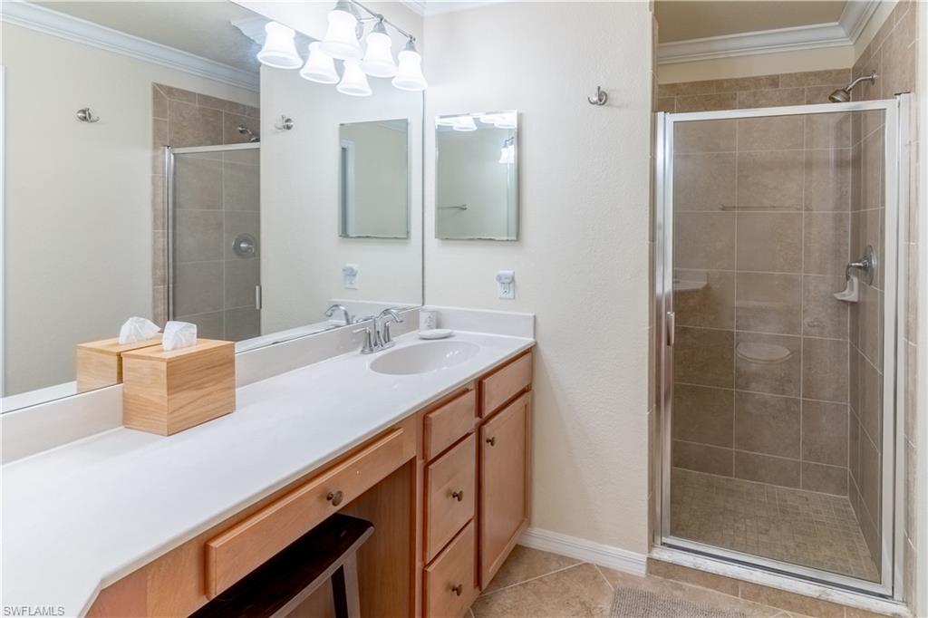 Bathroom featuring crown molding, a shower stall, vanity, a chandelier, and light tile patterned floors