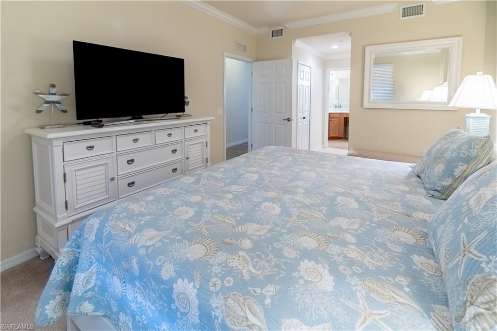 Bedroom with ornamental molding, light carpet, and ensuite bathroom