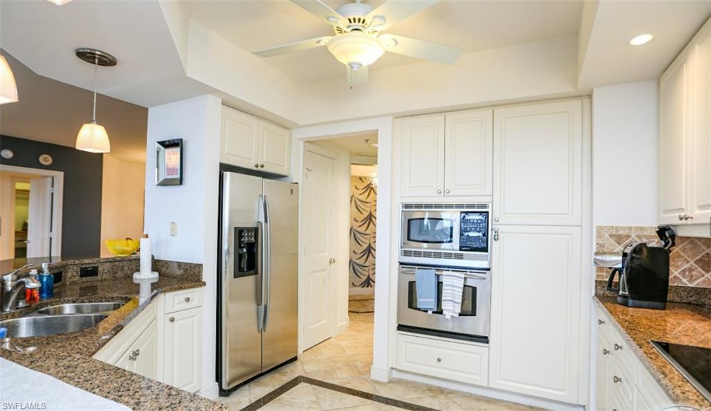 Kitchen featuring white cabinets, stainless steel appliances, dark stone countertops, a sink, and backsplash