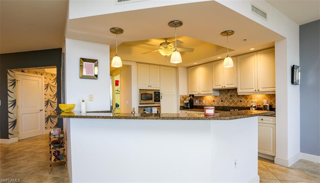 Kitchen with visible vents, stainless steel appliances, tasteful backsplash, a raised ceiling, and dark stone countertops