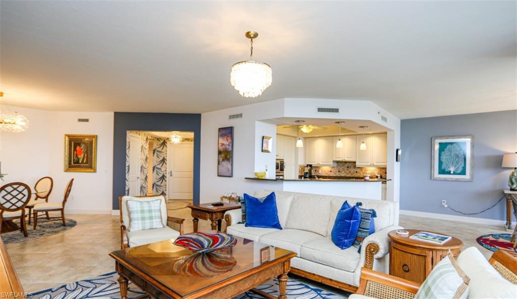 Living room with baseboards, a notable chandelier, visible vents, and light tile patterned floors
