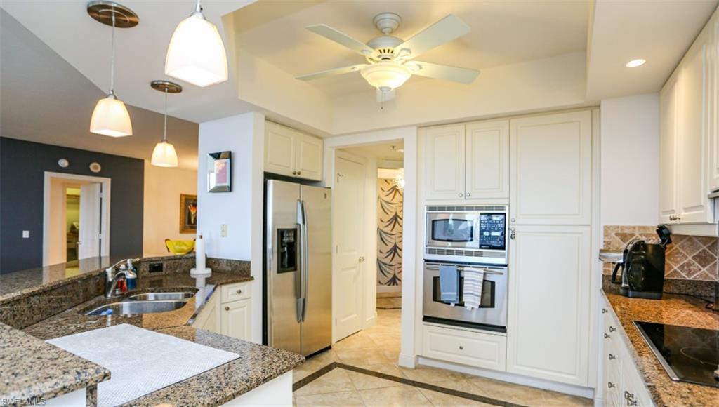 Kitchen featuring white cabinetry, decorative light fixtures, decorative backsplash, a sink, and appliances with stainless steel finishes