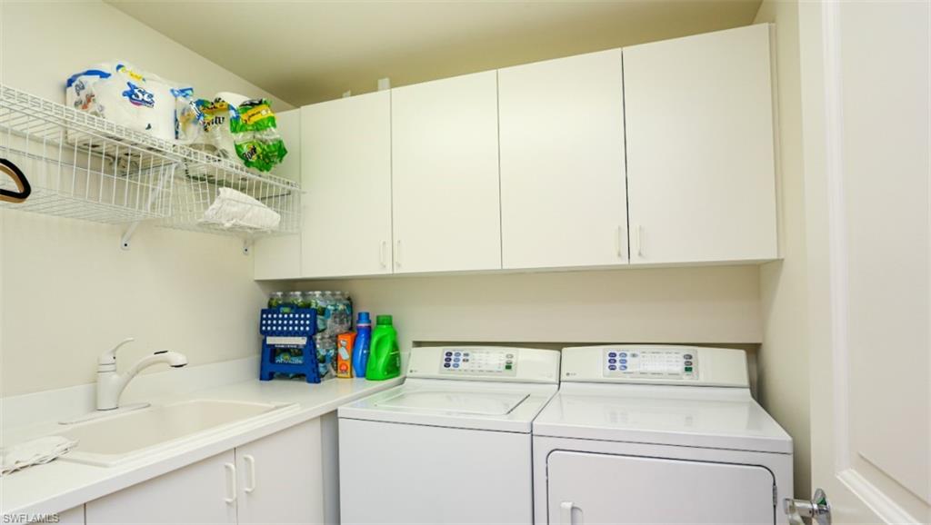 Clothes washing area featuring a sink, cabinet space, and washer and dryer