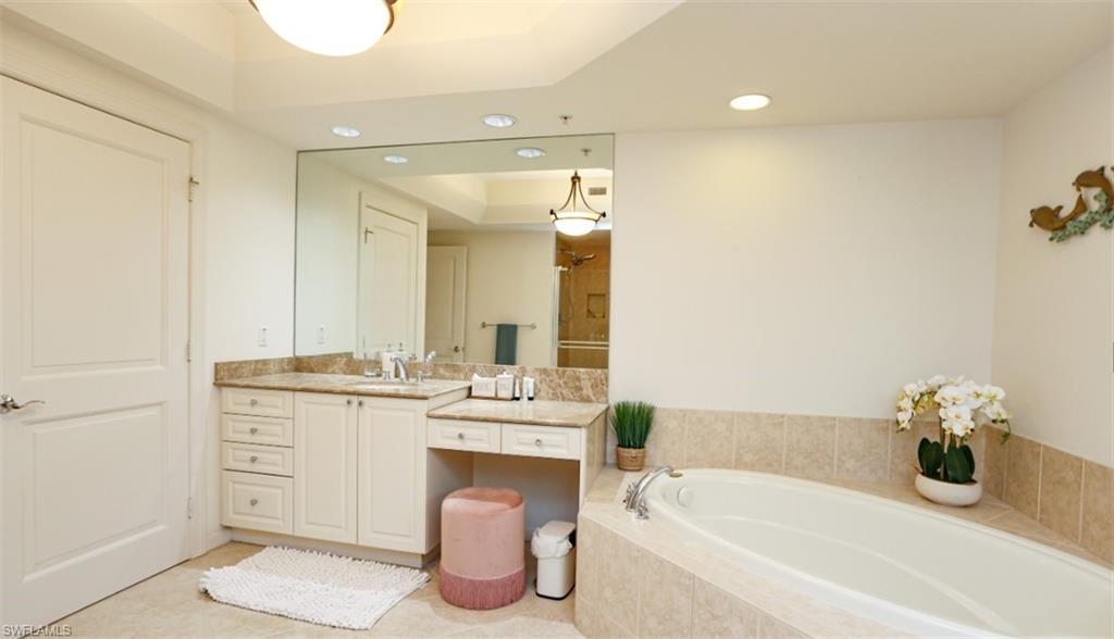 Full bathroom featuring walk in shower, recessed lighting, vanity, a tray ceiling, and a garden tub