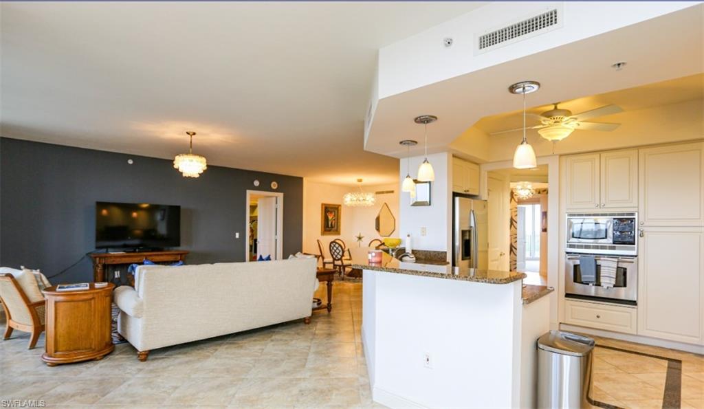 Kitchen with visible vents, appliances with stainless steel finishes, dark stone countertops, ceiling fan with notable chandelier, and hanging light fixtures