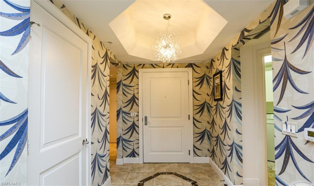 Entryway with an inviting chandelier, a tray ceiling, and baseboards