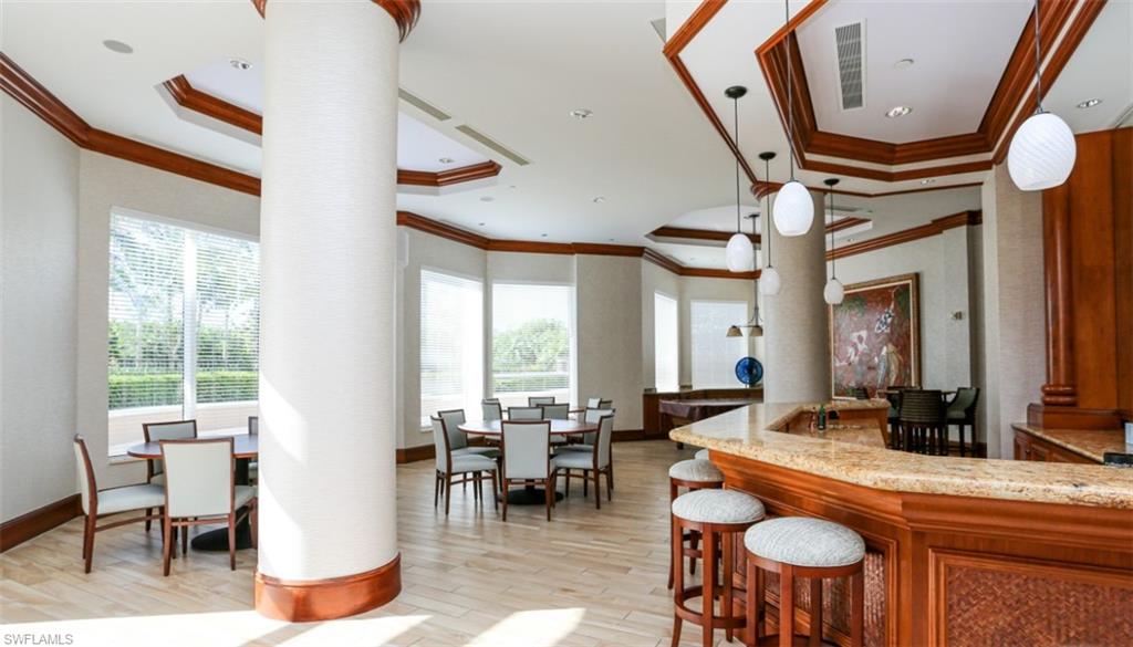 Kitchen with decorative columns, a raised ceiling, ornamental molding, and light wood-style floors