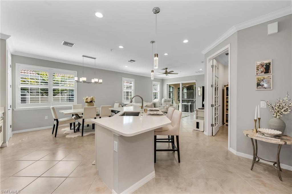 Kitchen featuring ornamental molding, an island with sink, healthy amount of natural light, a breakfast bar, and ceiling fan