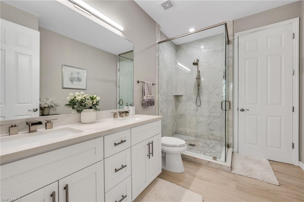 Bathroom with double vanity and a marble finish shower