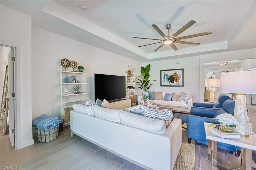Living room with ceiling fan, a tray ceiling, and wood finish floors