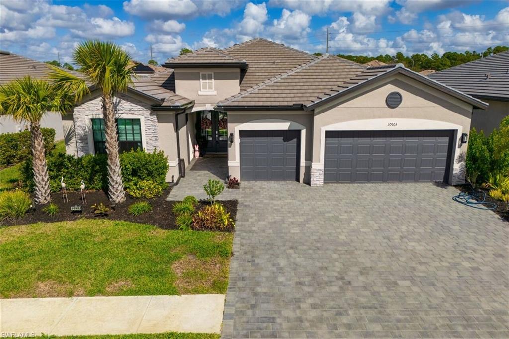 View of front of home featuring an attached garage, stucco siding, decorative driveway, and stone siding