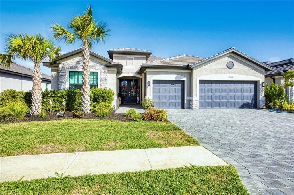 View of front of property with stone siding, a garage, stucco siding, french doors, and decorative driveway