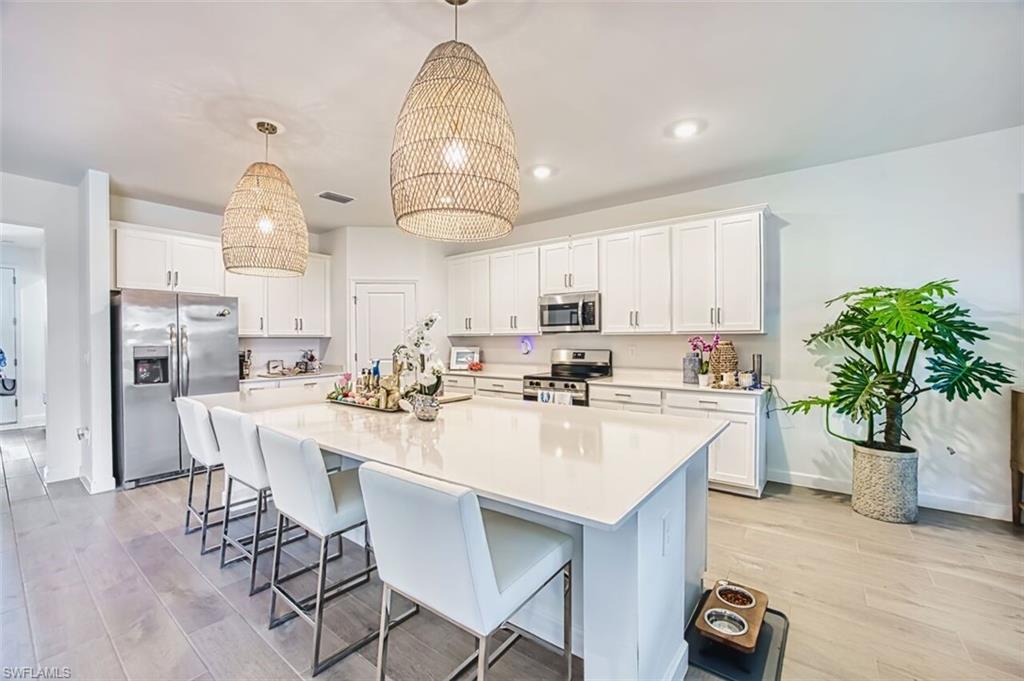 Kitchen with stainless steel appliances, light wood finished floors, and a kitchen bar