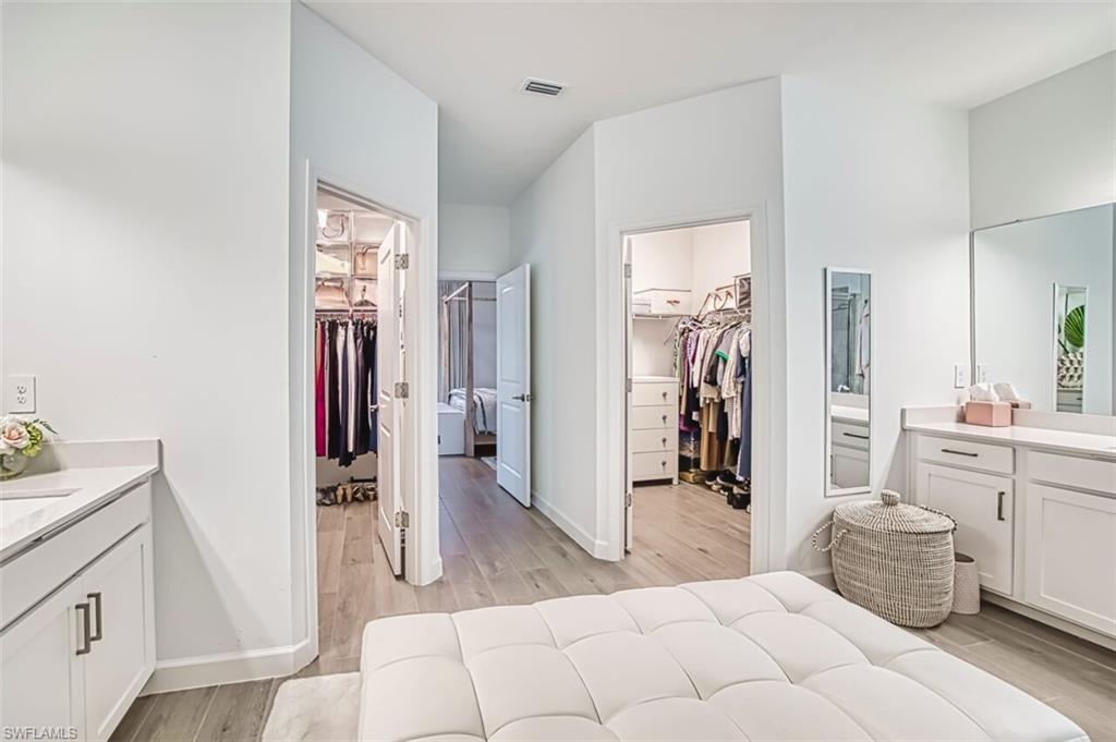 Bedroom with connected bathroom, a spacious closet, and light wood-style flooring