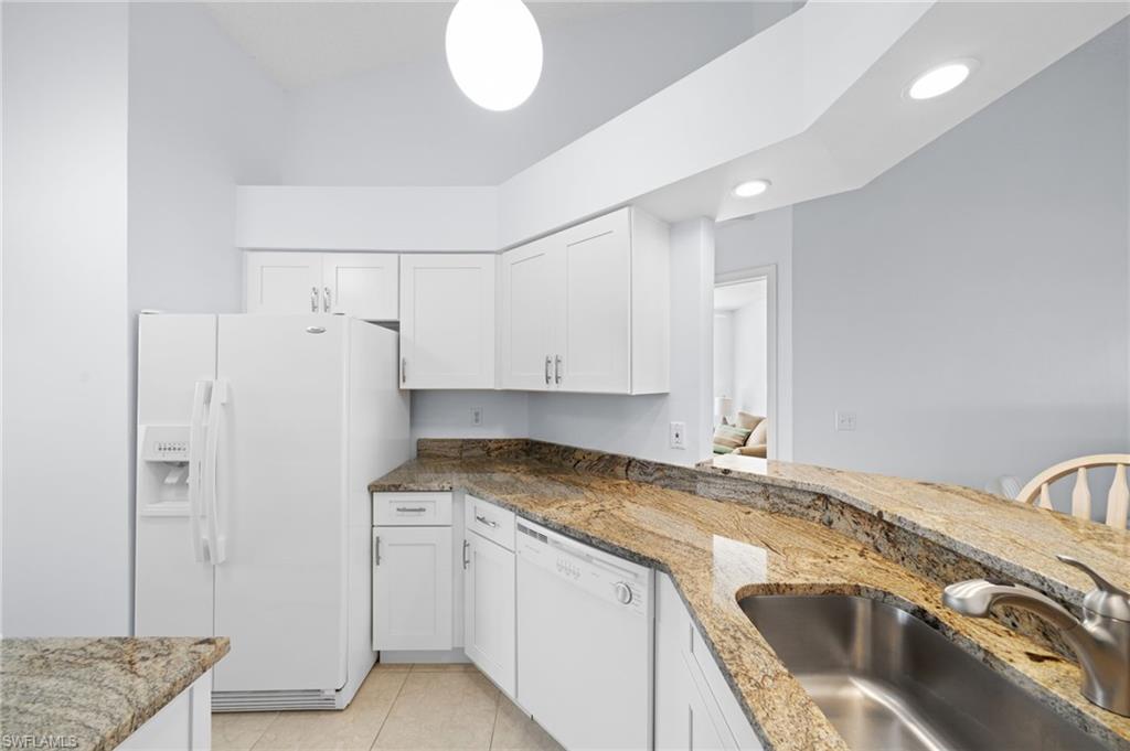 Kitchen with white appliances, white cabinetry, light stone countertops, light tile patterned flooring, and recessed lighting