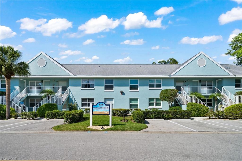 View of building exterior featuring stairway and uncovered parking