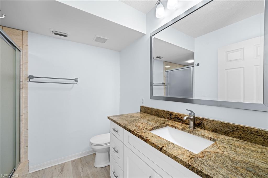Full bathroom with vanity, light wood-type flooring, and a stall shower