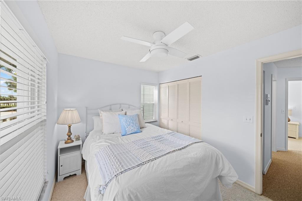 Bedroom featuring light colored carpet, a ceiling fan, a closet, and a textured ceiling