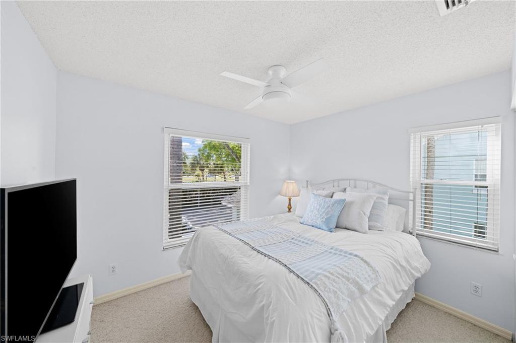 Bedroom with light colored carpet, a textured ceiling, and ceiling fan