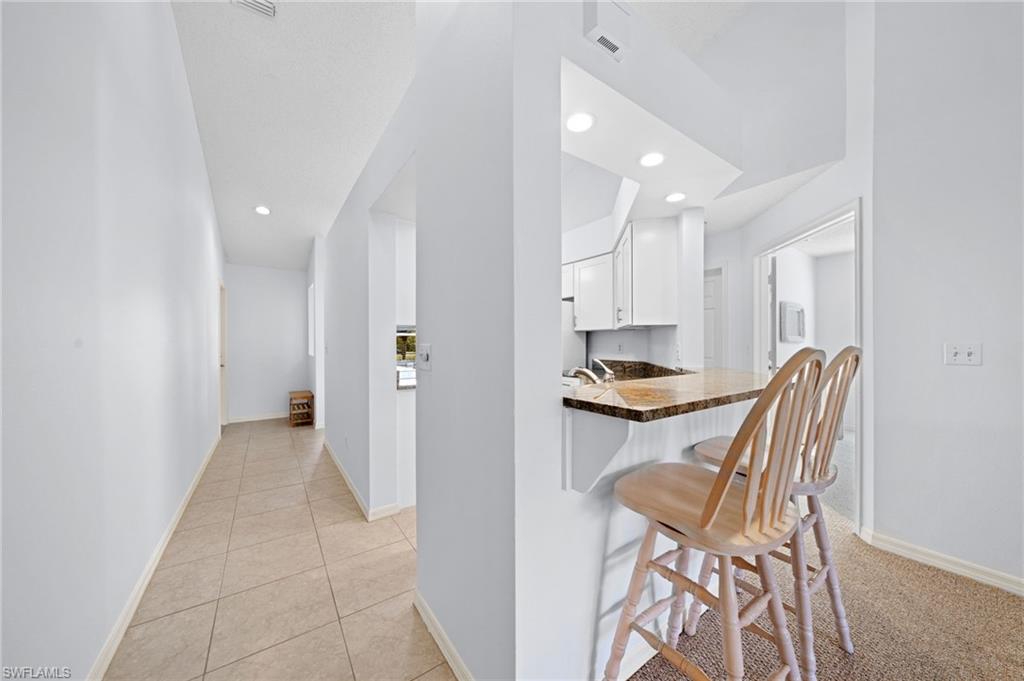 Kitchen featuring white cabinetry, a kitchen breakfast bar, a peninsula, recessed lighting, and light tile patterned flooring