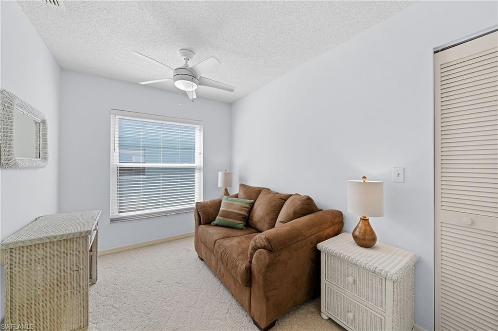 Living room featuring ceiling fan, light colored carpet, and a textured ceiling