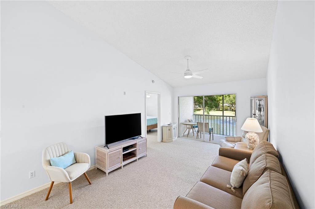 Living area with light carpet, lofted ceiling, and a ceiling fan