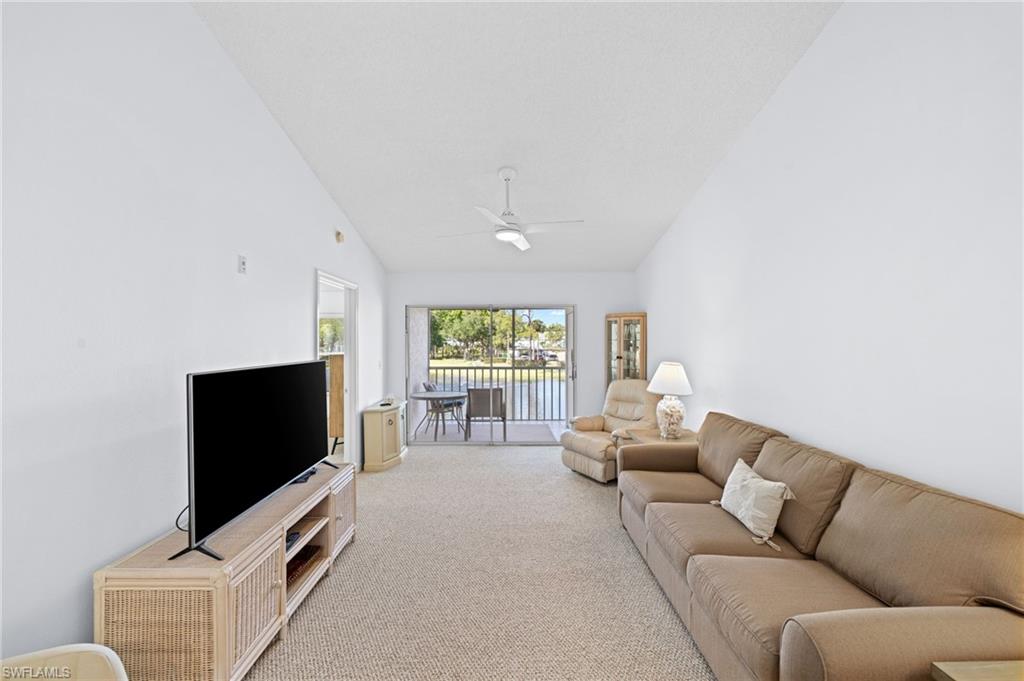Living room with vaulted ceiling, light colored carpet, and ceiling fan
