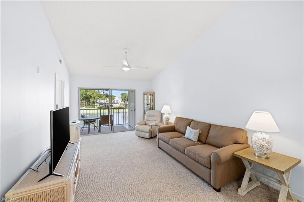 Living room with light carpet, vaulted ceiling, and ceiling fan