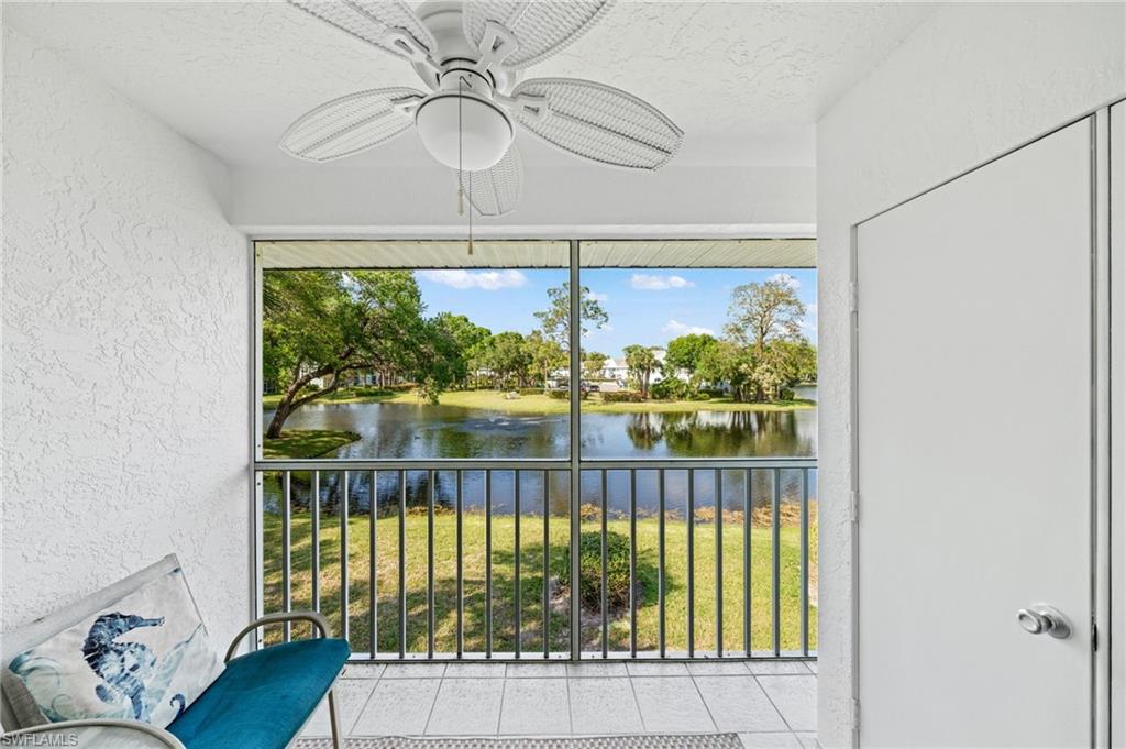 Unfurnished sunroom with a ceiling fan, a water view, and a balcony