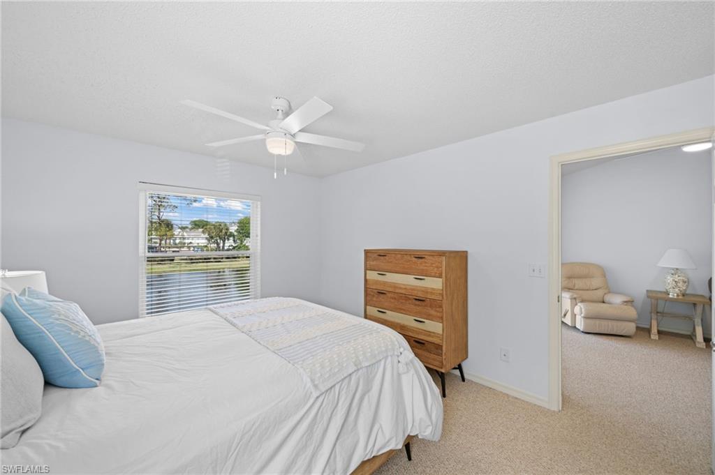 Bedroom with light carpet, a ceiling fan, and a water view