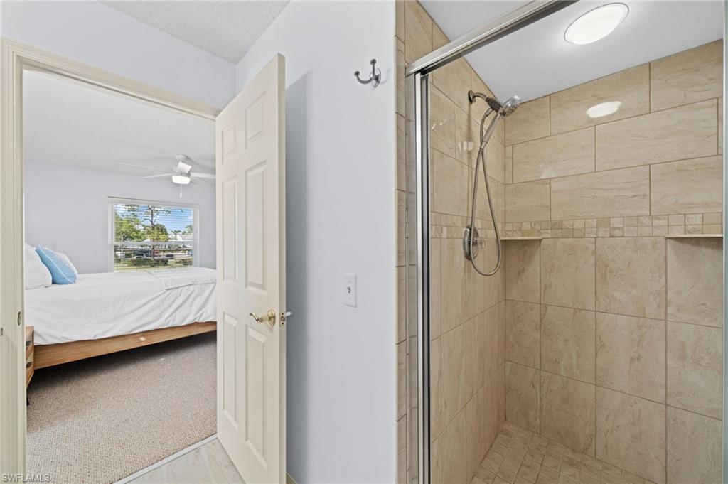 Full bathroom featuring light colored carpet, ensuite bath, a stall shower, and ceiling fan