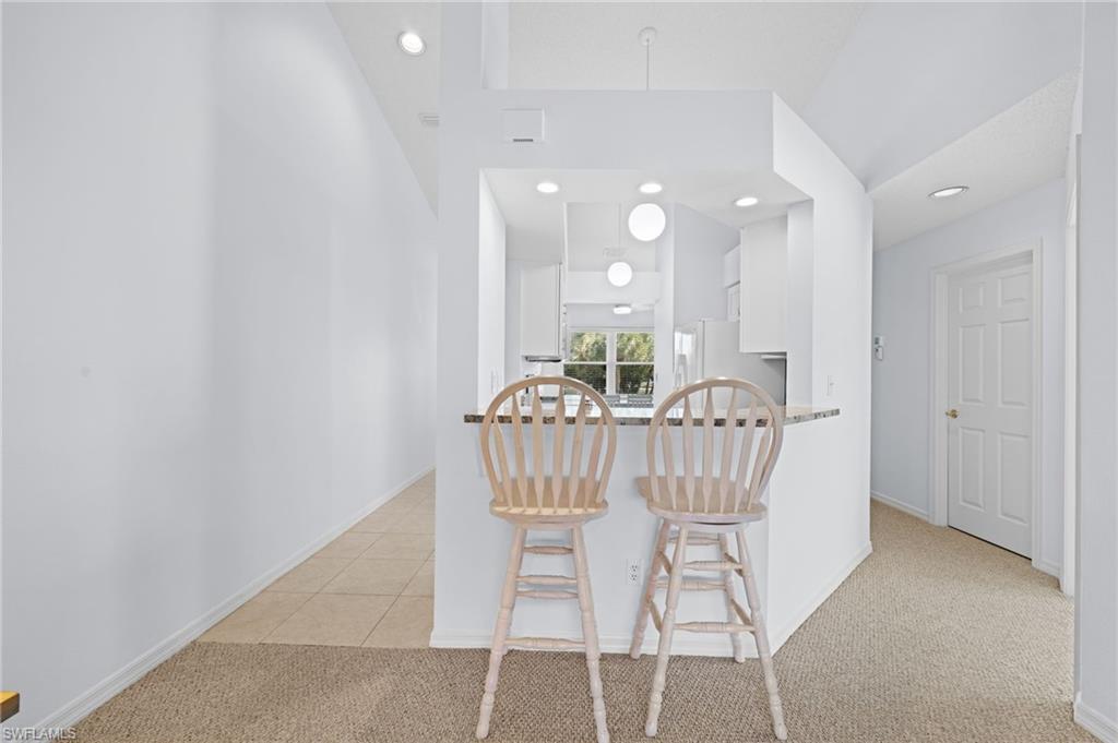 Kitchen featuring white cabinets, light colored carpet, recessed lighting, a peninsula, and a kitchen bar