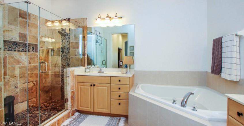 Full bathroom featuring vanity, a stall shower, and a garden tub